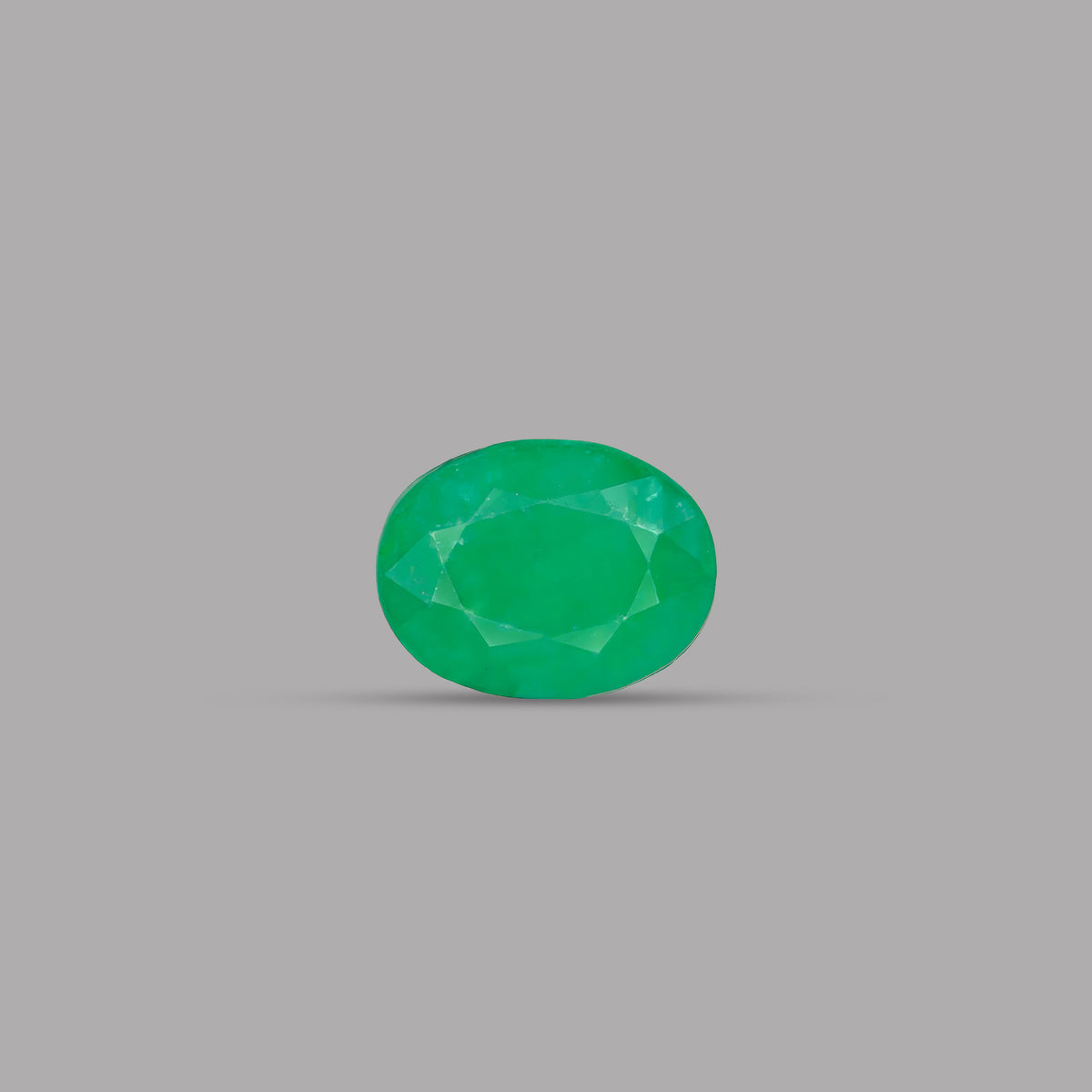 A single oval-cut green gemstone, faceted with multiple geometric planes, centered on a solid gray background.